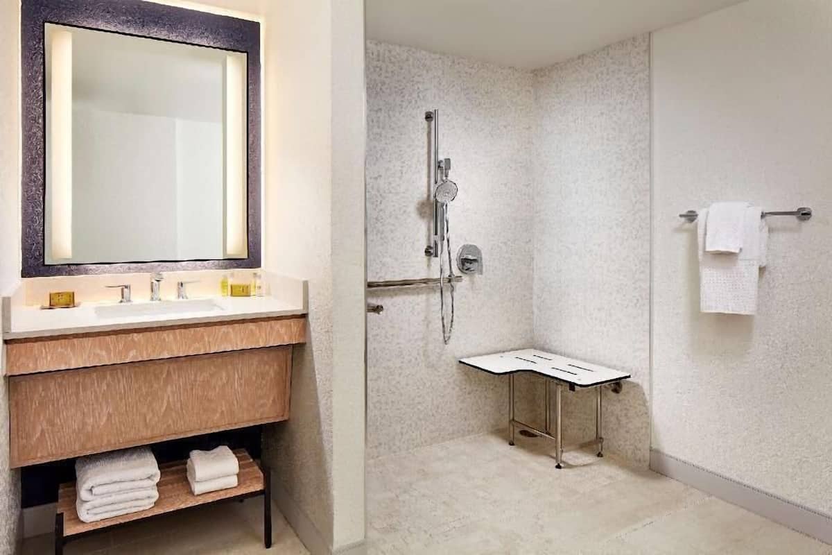 A bathroom with a mirror, sink, and shower.