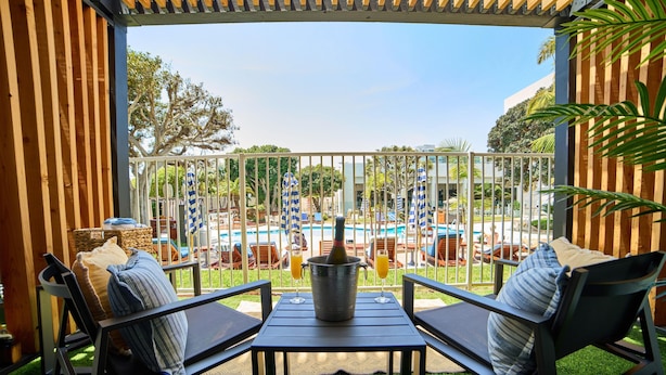 An outdoor seating area with two chairs and a table, a metal bucket with a bottle, and two glasses of orange juice. - Hotel MDR Marina del Rey - a DoubleTree by Hilton (Marina del Rey)