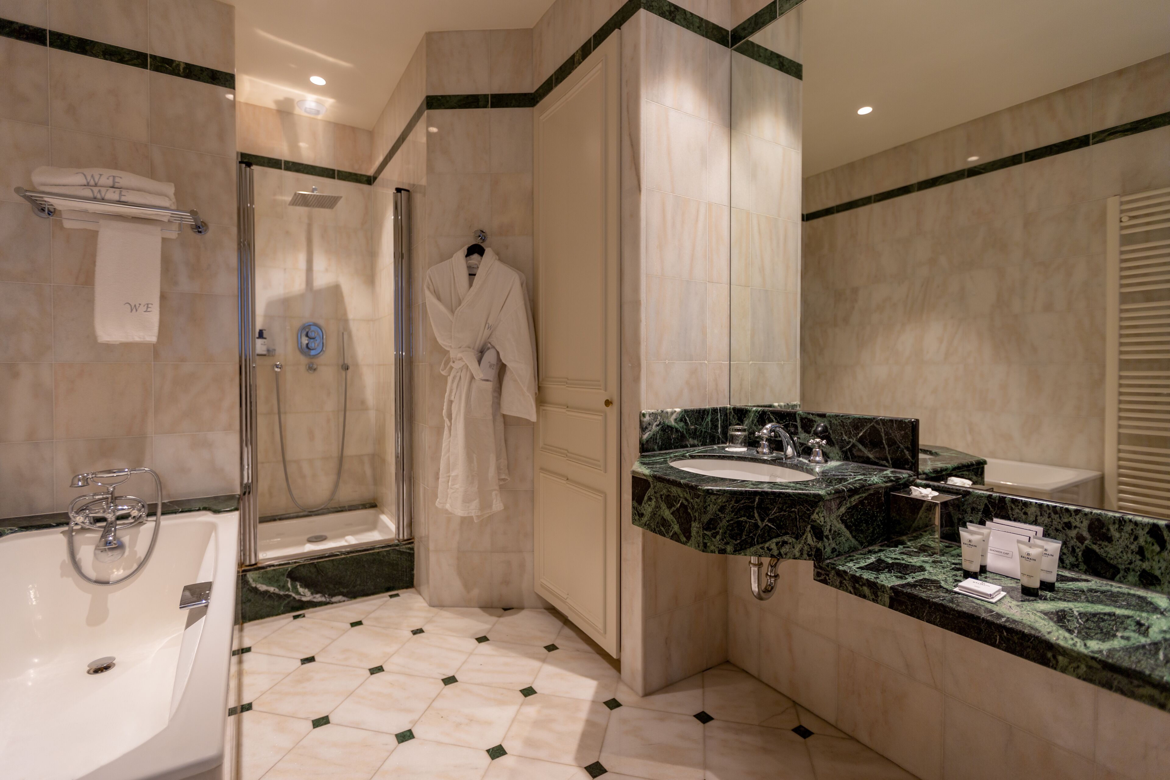 A modern bathroom with a glass-enclosed shower, a white bathtub, and a marble countertop sink.