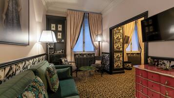 A room with a green sofa, a red dresser, a leopard print carpet, and a large window with curtains.