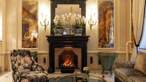 Una sala de estar lujosa con chimenea, sillones estampados y una mesita de centro.