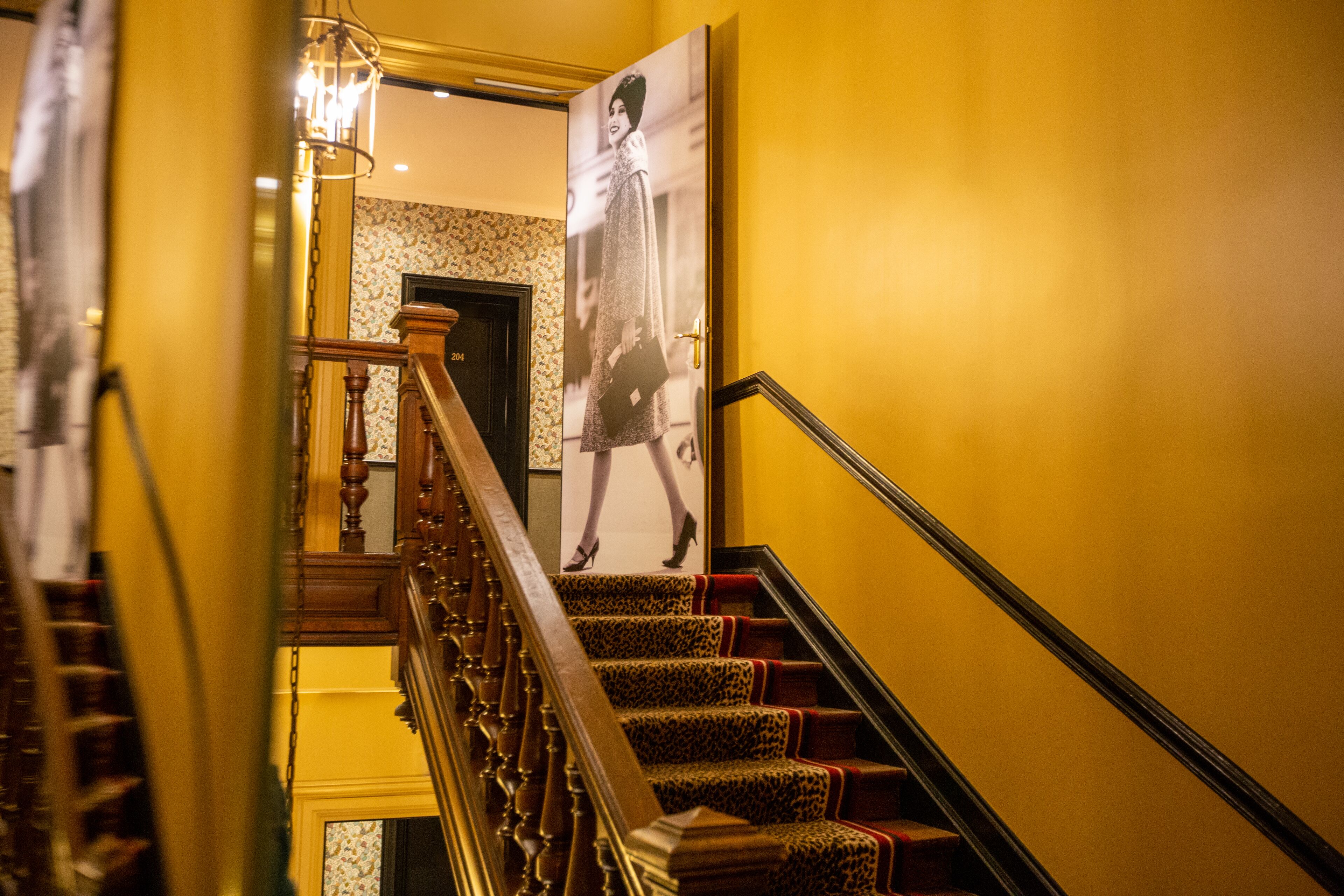 A staircase with wooden railings and leopard print carpet.