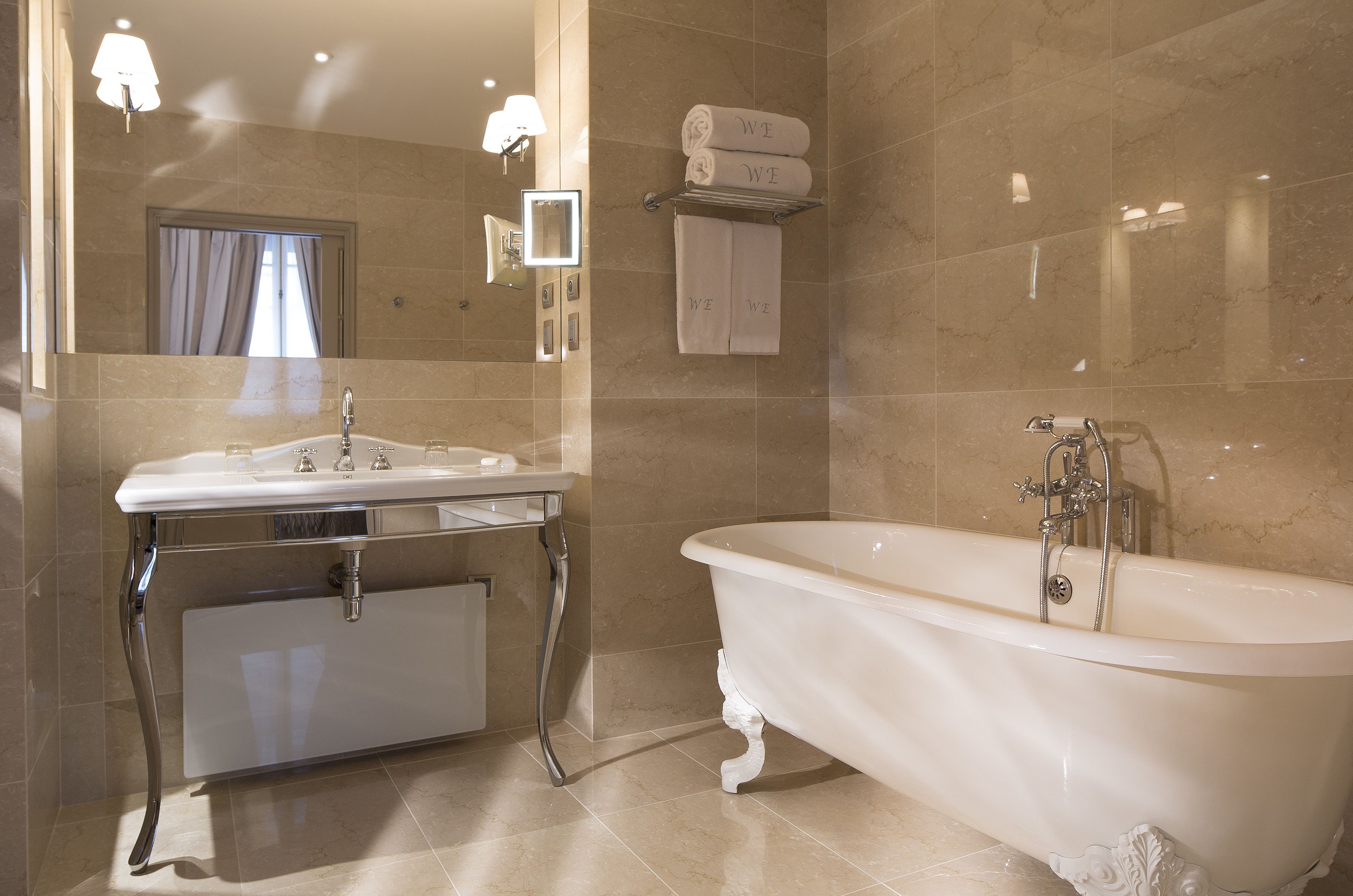 A modern bathroom with a freestanding bathtub, a vanity with a mirror, and a towel rack with folded towels.