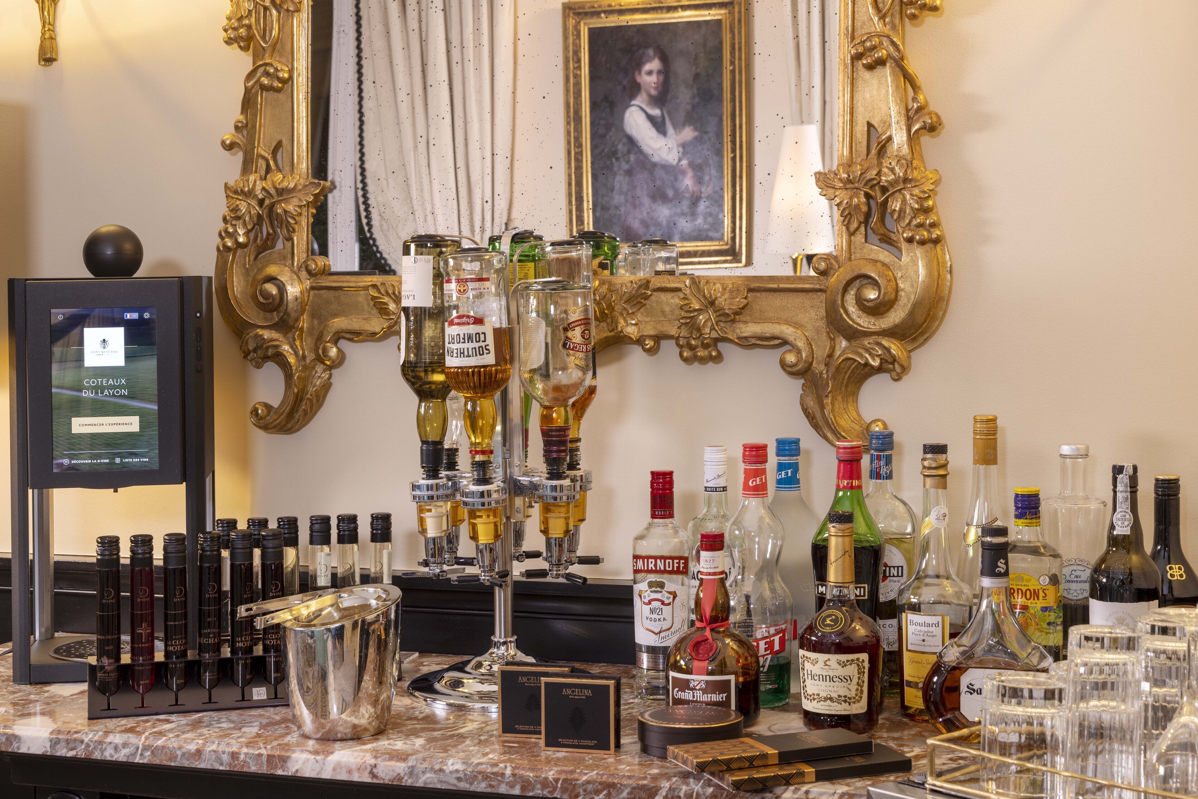 Zona de bar con una variedad de botellas de licor, vasos y un espejo decorativo.