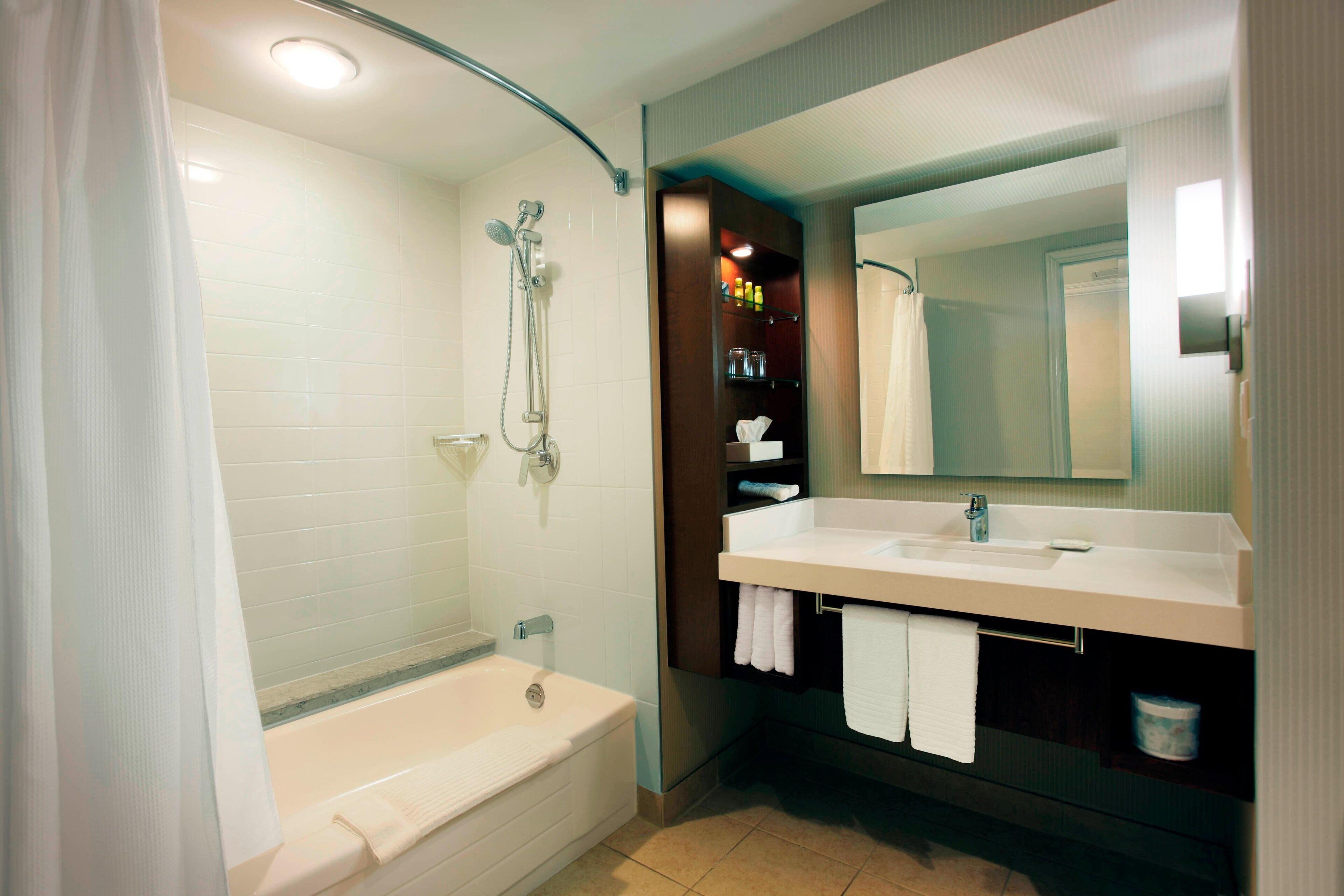 A modern bathroom with a bathtub, shower, vanity, and a large mirror.