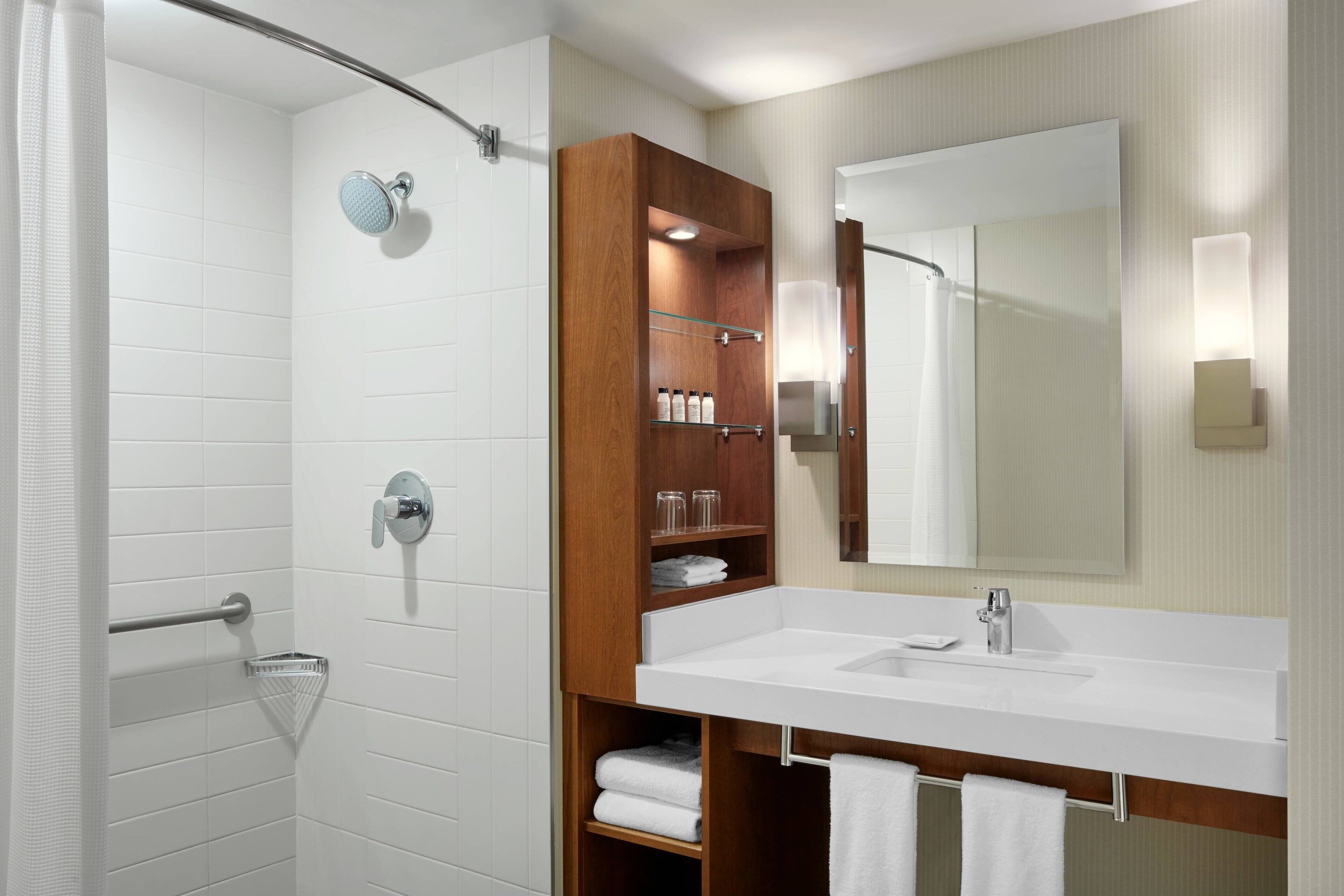 Un baño moderno con ducha, tocador con espejo y un perchero para toallas.