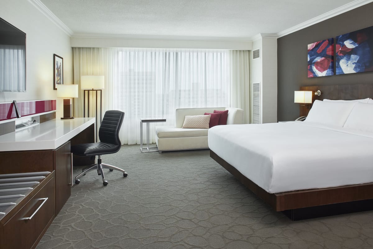 A hotel room with a bed, desk, chair, and a small table.