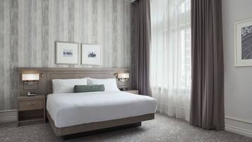 A large bed with a wooden headboard, two bedside tables with lamps, and a patterned carpet.
