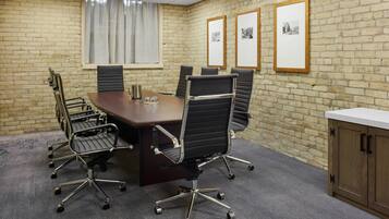 A conference room with a brick wall, a large table, and six office chairs.