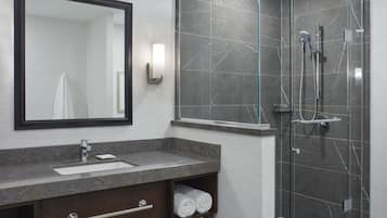 Een moderne badkamer met een marmeren wastafel, een grote spiegel, een douche met glazen wanden en een handdoekplank.