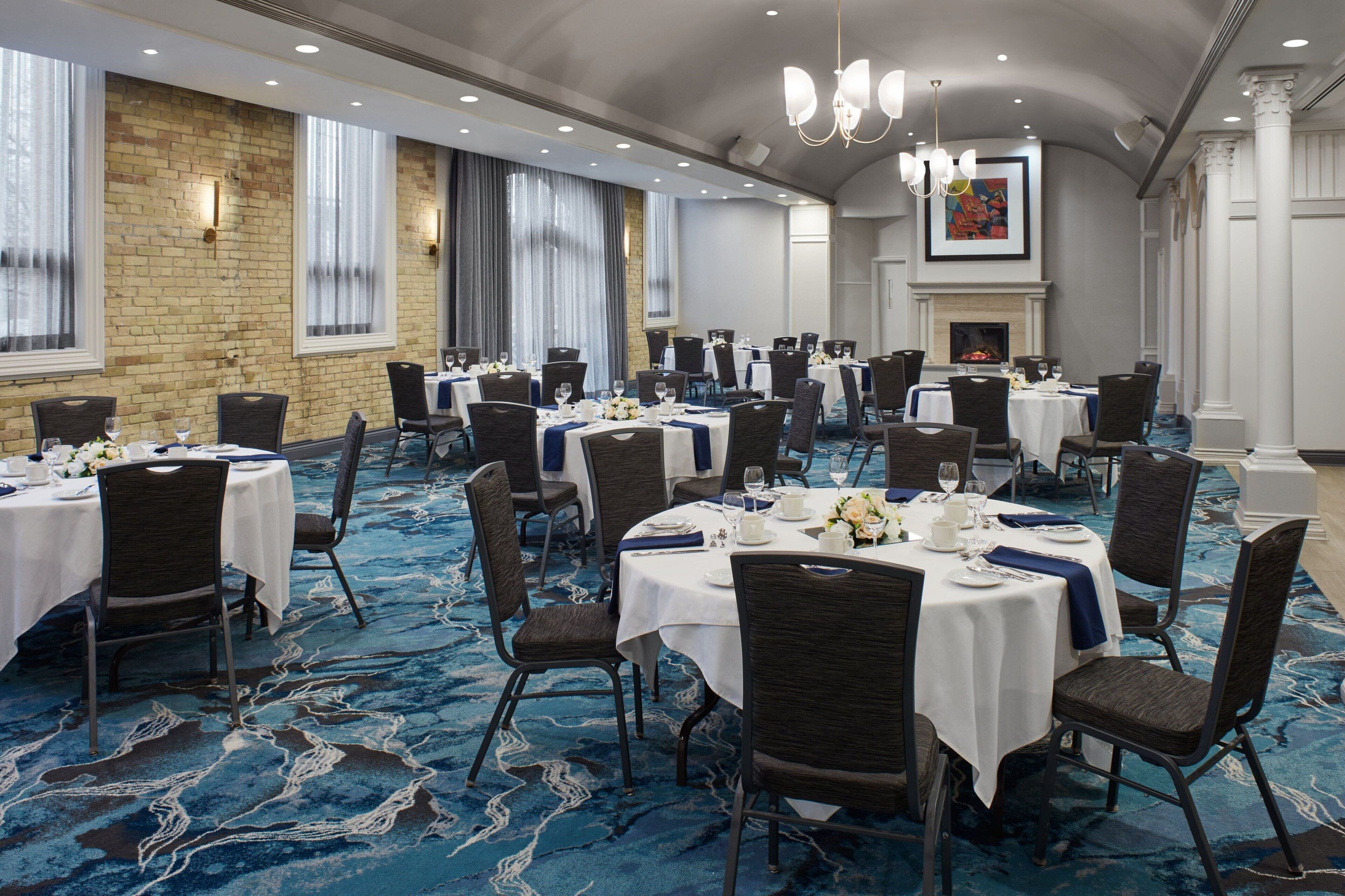 A banquet hall with round tables, chairs, and a blue carpet.