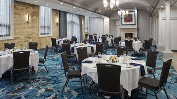A banquet hall with round tables, chairs, and a blue carpet.