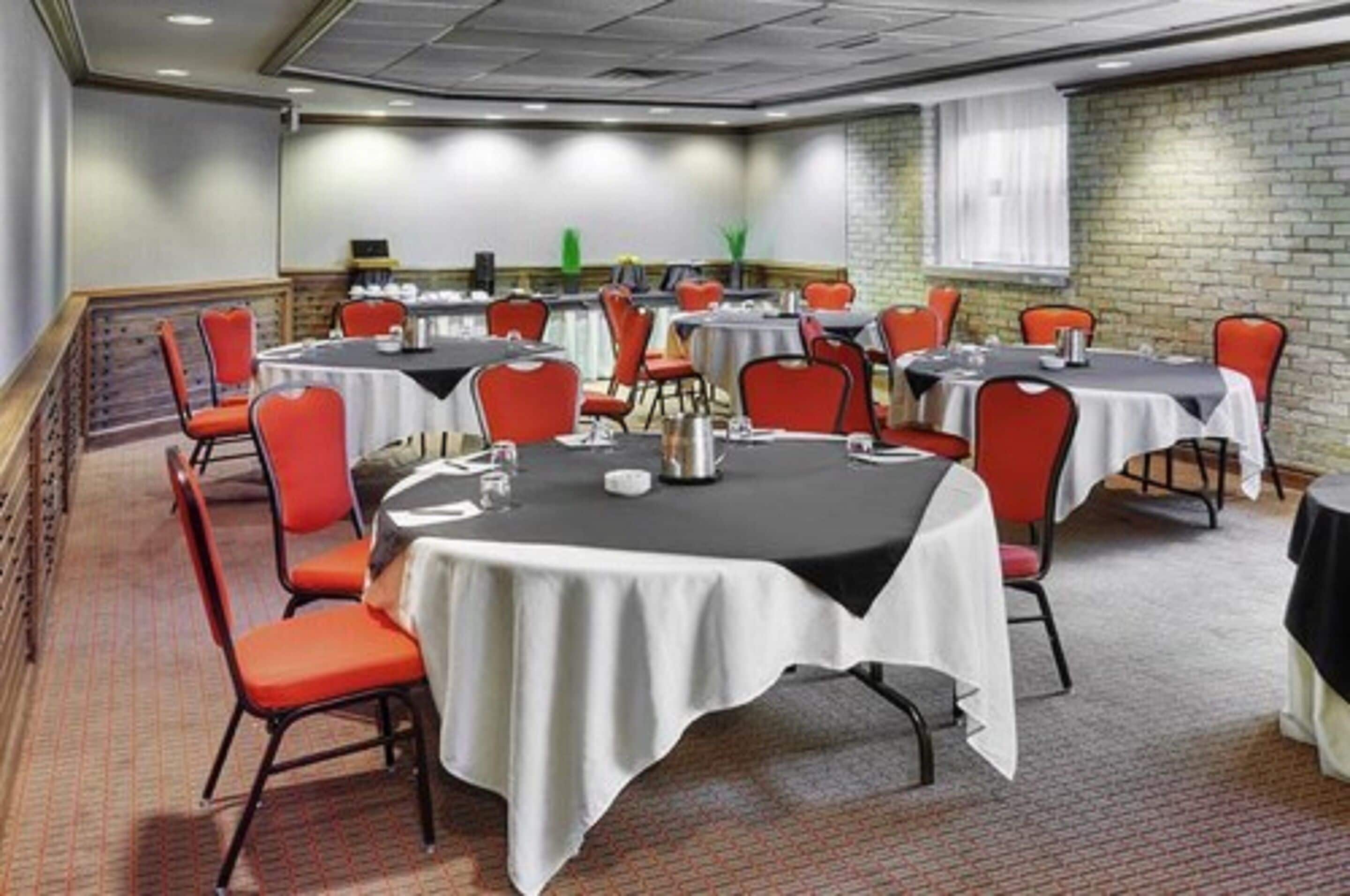 Une salle de conférence dotée de plusieurs tables et chaises, ainsi que de plaques nominatives et de carafes d’eau.
