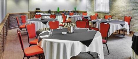 Une salle de conférence dotée de plusieurs tables et chaises, ainsi que de plaques nominatives et de carafes d’eau.