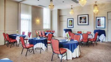 Un salón de conferencias con mesas y sillas, candelabros y cuadros en las paredes.