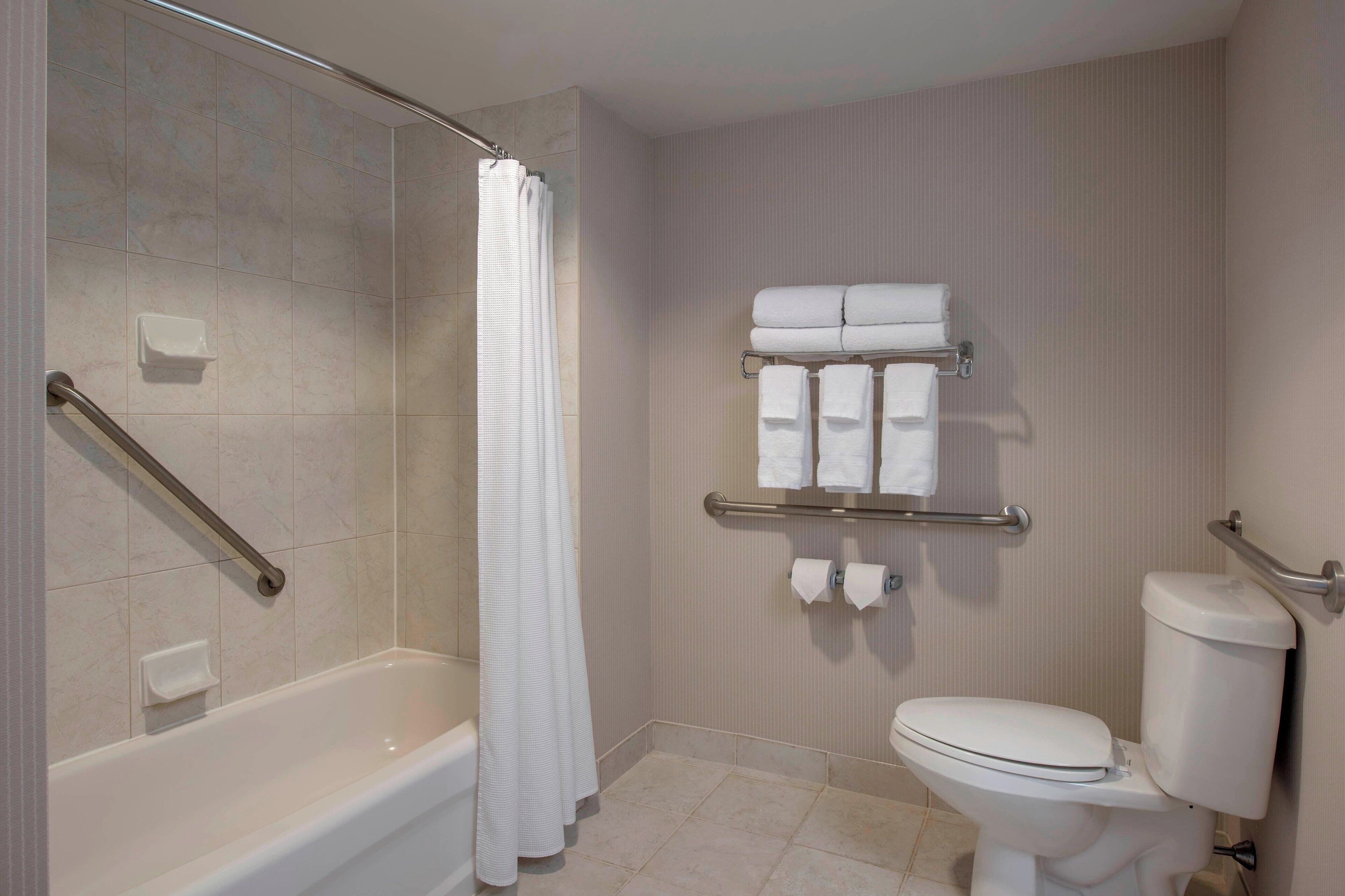 A bathroom with a bathtub, toilet, and towel rack.