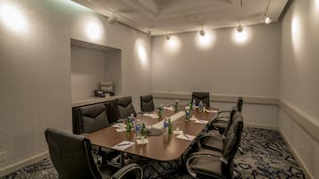 A conference room with a long table, black leather chairs, water bottles, and a carpeted floor.