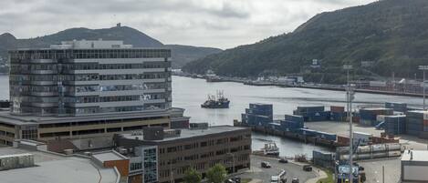 A modern building with a flat roof, a parking lot, and a river with boats.