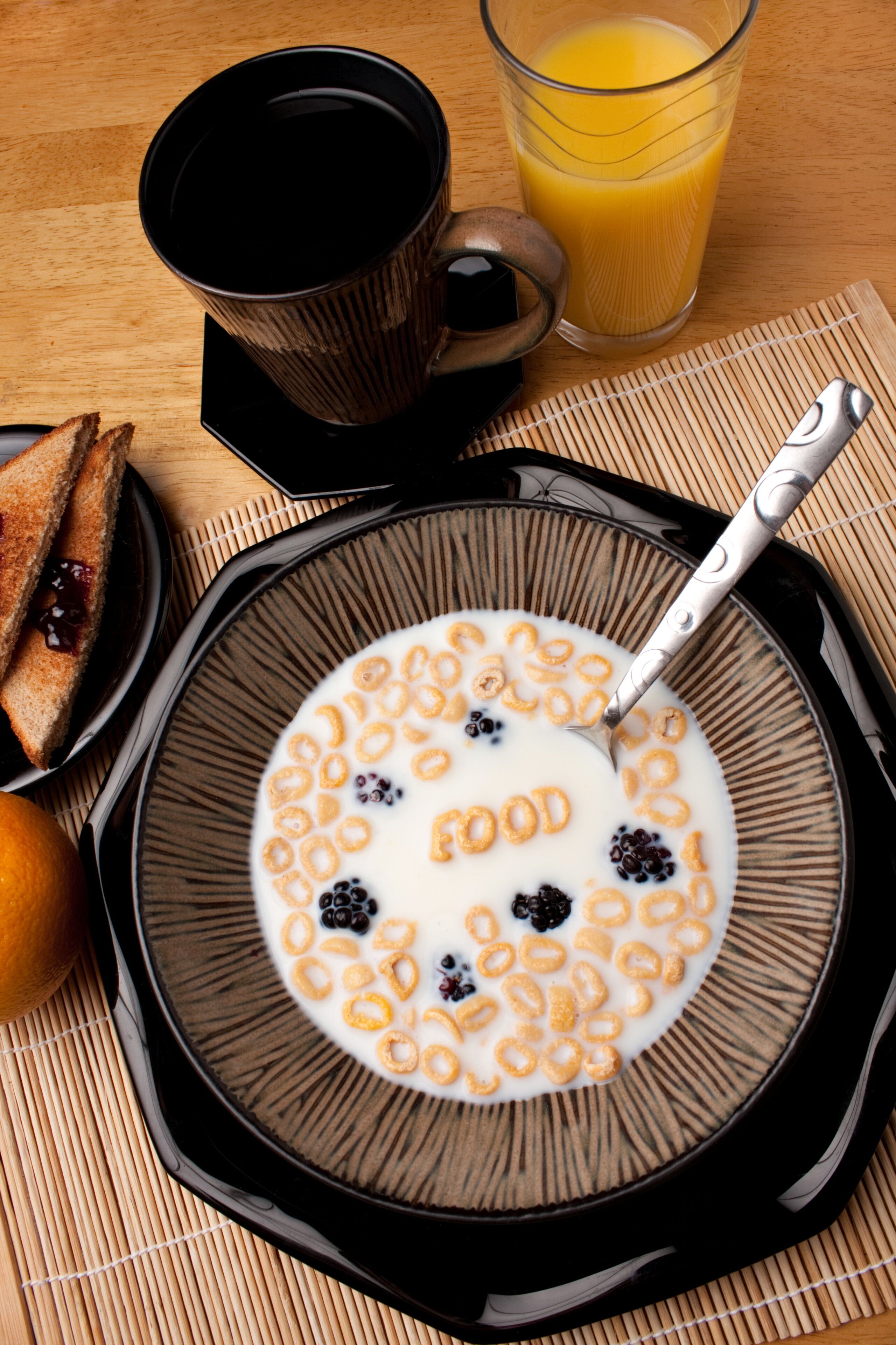 Una escena de desayuno con cereal, leche, tostadas y un vaso de jugo de naranja sobre una mesa de madera.