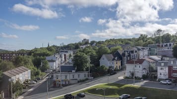 A residential street with houses, parked cars, and a clear sky.