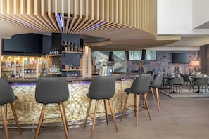 A modern bar area with a curved counter, bar stools, and a variety of liquor bottles. - Delta Hotels by Marriott Sherbrooke Conference Centre (Sherbrooke)