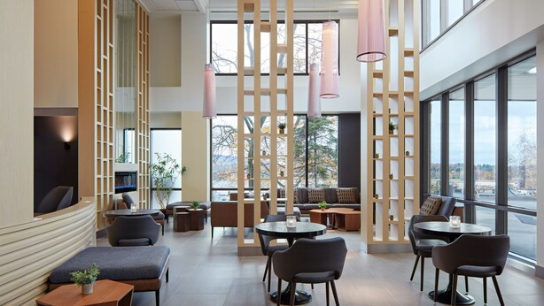 A modern interior with seating areas, tables, and large windows offering views. - Delta Hotels by Marriott Sherbrooke Conference Centre (Sherbrooke)