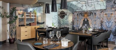 A modern dining area with a wooden table, black chairs, and a marble wall with a map design.