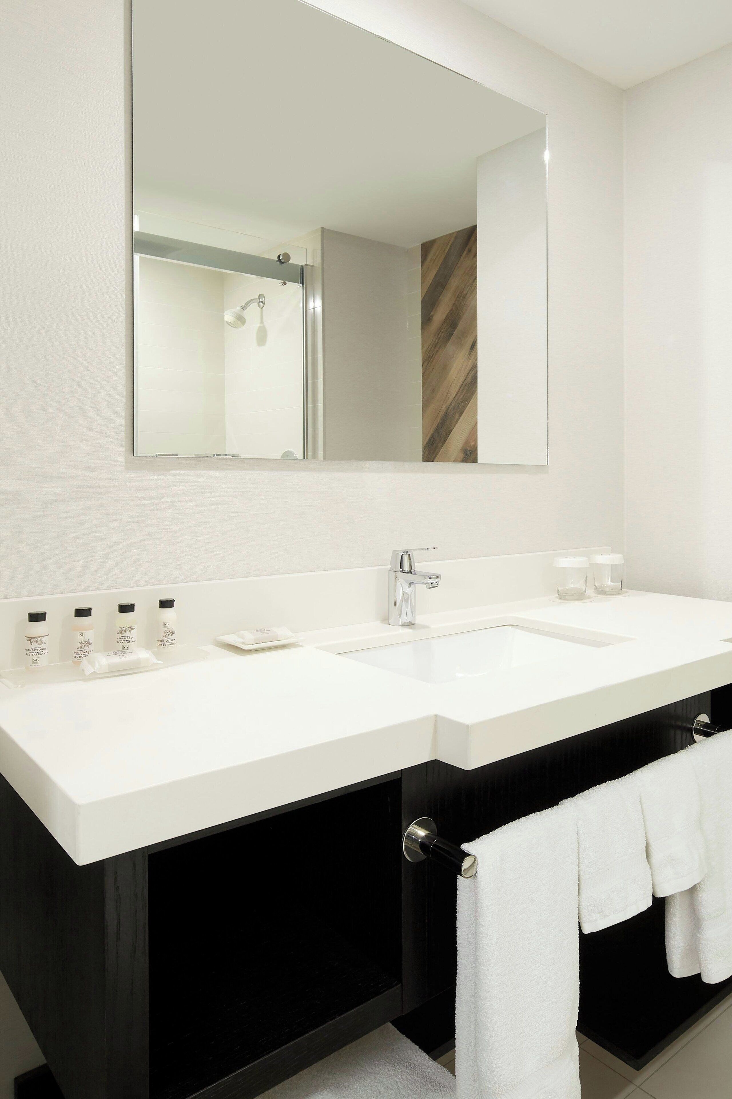 A modern bathroom with a large mirror, two sinks, and a black vanity.