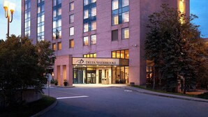 A multi-story hotel with a prominent 'Hotel Delta' sign, a glass facade, and a well-lit entrance. - Delta Hotels by Marriott Sherbrooke Conference Centre (Sherbrooke)
