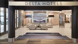 Der Eingang eines Delta Hotels mit modernem Interieur, darunter ein Empfangsbereich mit Sitzgelegenheiten und einem großen Bildschirm.