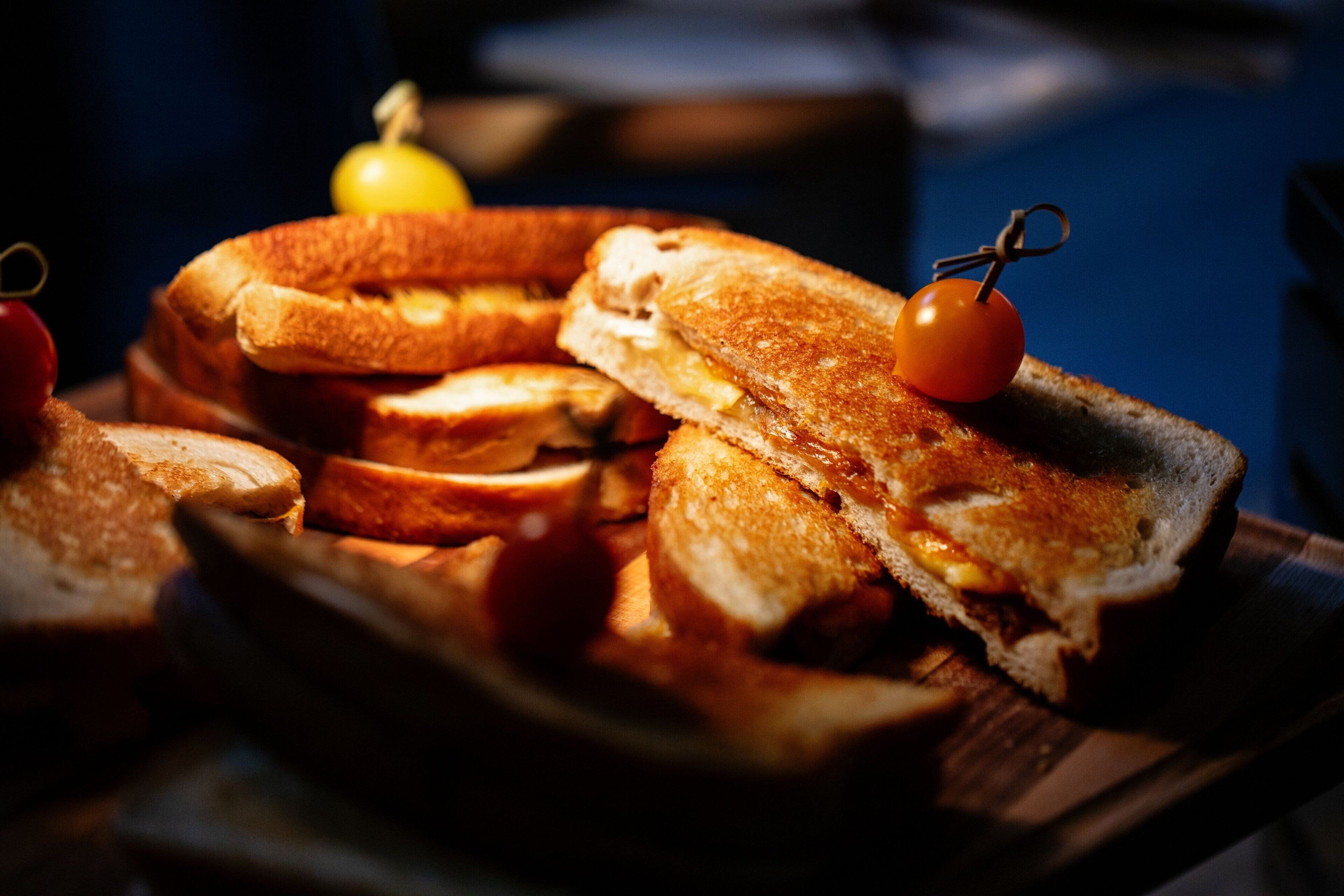 Un plateau en bois avec des sandwichs grillés et des tomates cerises.