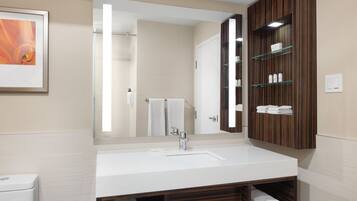 Un baño moderno con un espejo grande, lavamanos blanco y tocador de madera.