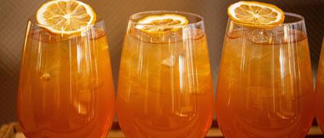 Three glasses of amber-colored beverage with a slice of orange garnish on a wooden surface.
