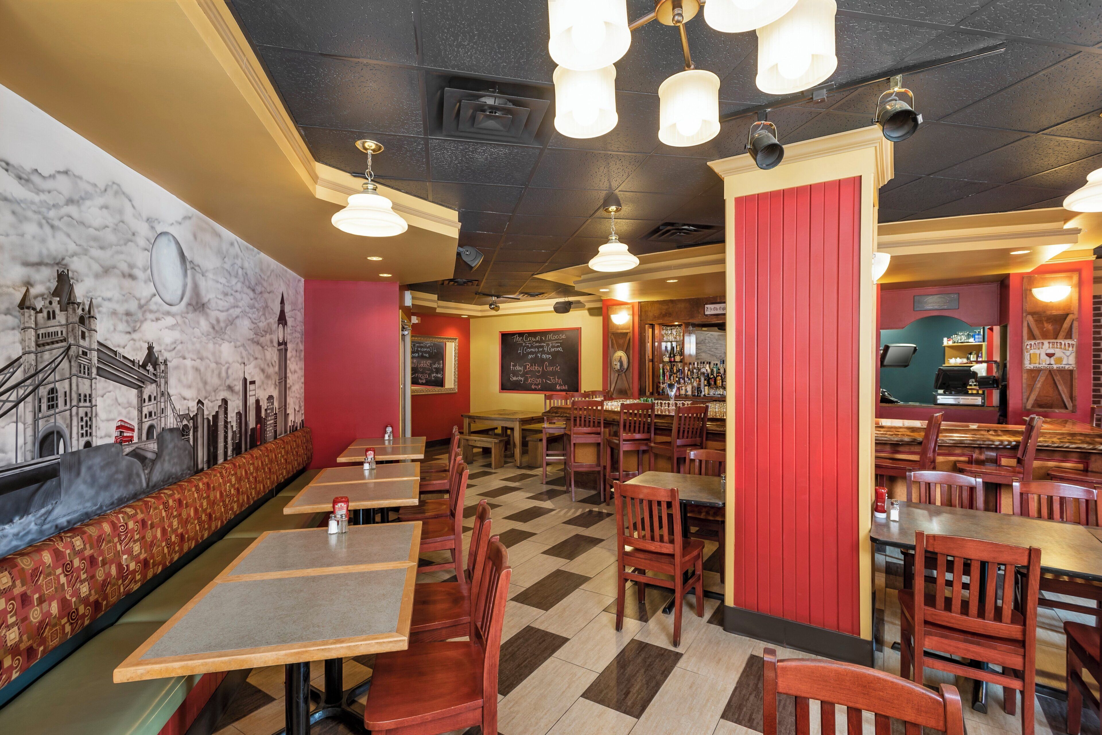 A restaurant interior with booths, tables, and a mural of a cityscape.