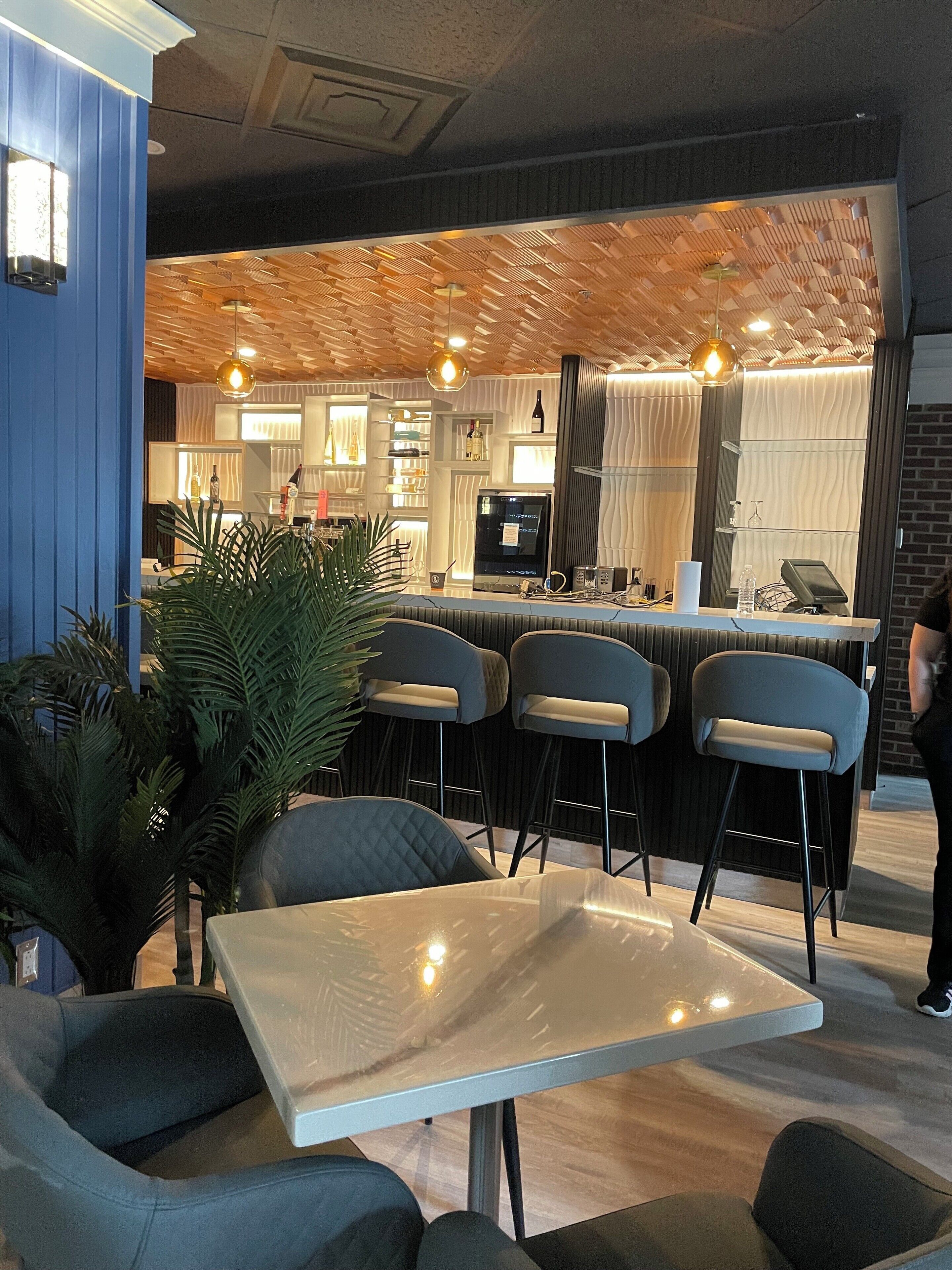 Un moderno bar con techo de madera, taburetes y una barra con caja registradora.