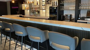 A modern bar area with a long counter, bar stools, and a variety of bottles and glasses. - Holiday Inn Sydney - Waterfront by IHG (Sydney)
