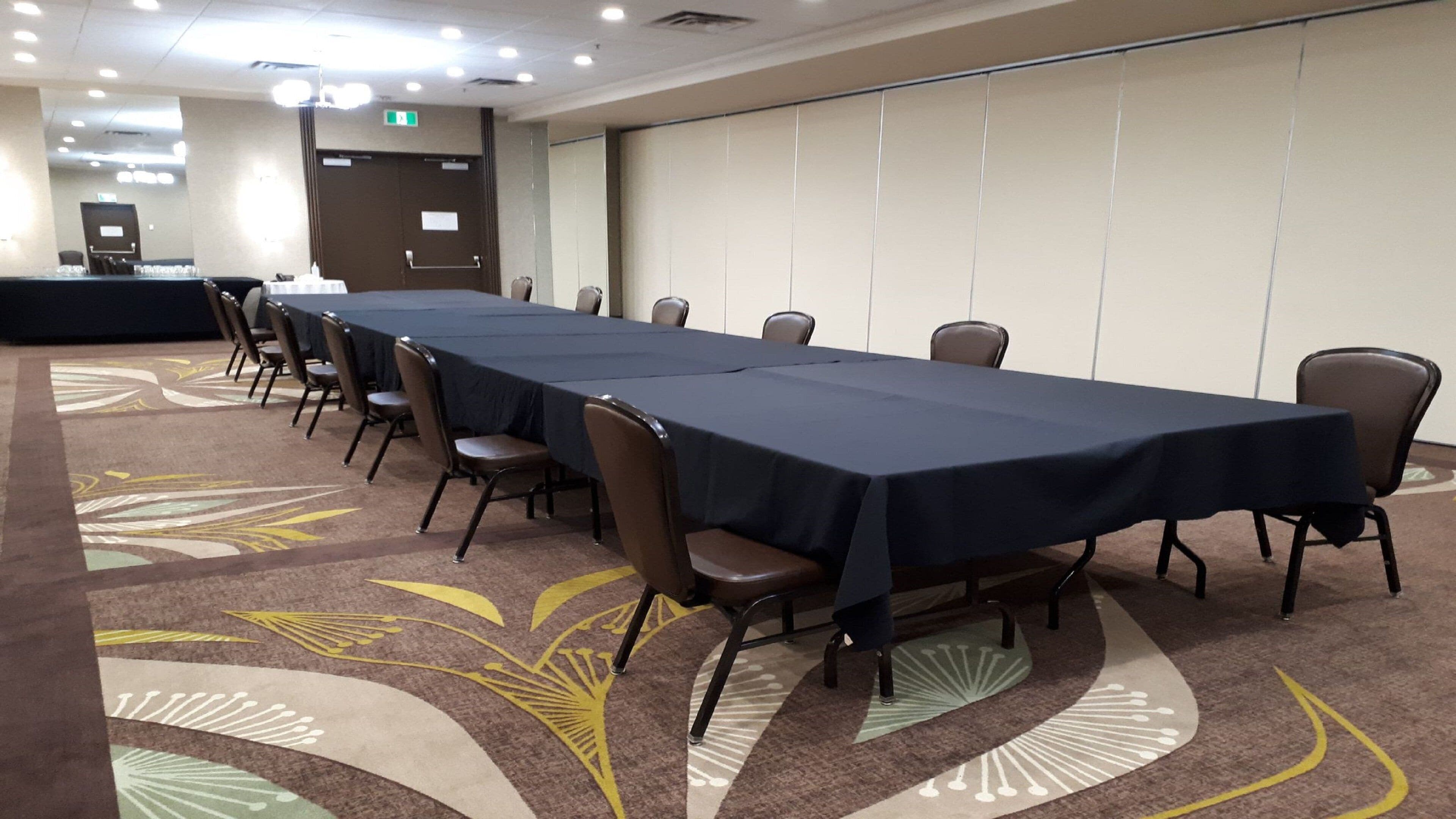 A conference room with a long table, chairs, and a carpeted floor.