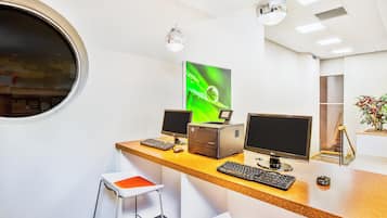 Un espacio de oficina moderno con un ventanal redondo, dos escritorios con computadoras y una planta.