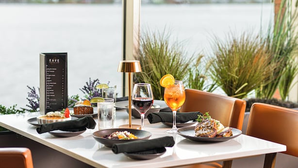 A dining table set with plates, glasses, and a menu, overlooking a body of water. - Holiday Inn Sydney - Waterfront by IHG (Sydney)
