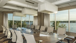 A conference room with a large table, chairs, and a view of a lake. - Holiday Inn Sydney - Waterfront by IHG (Sydney)