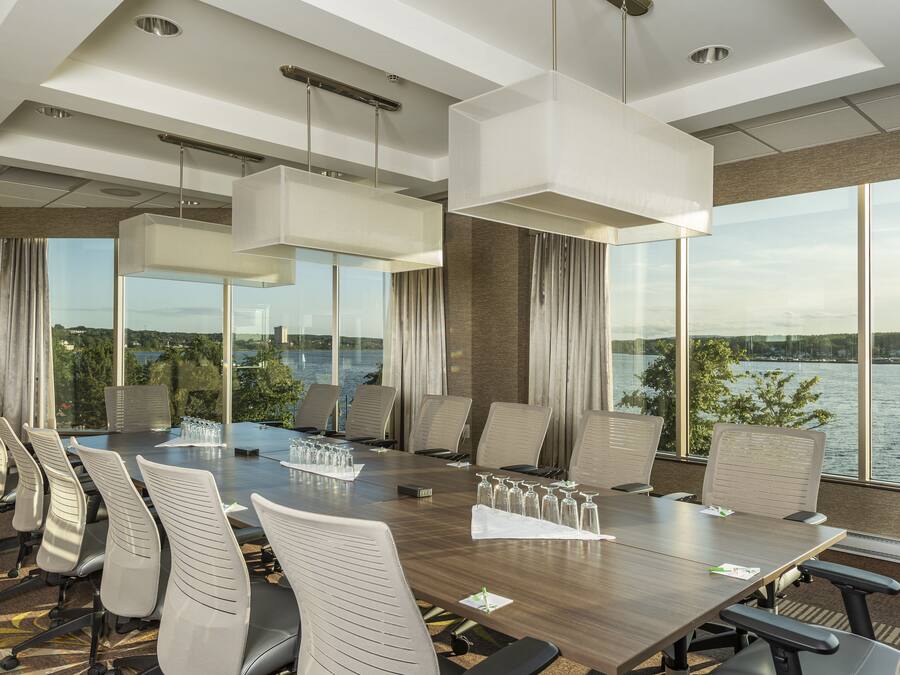 A conference room with a large table, chairs, and a view of a lake.