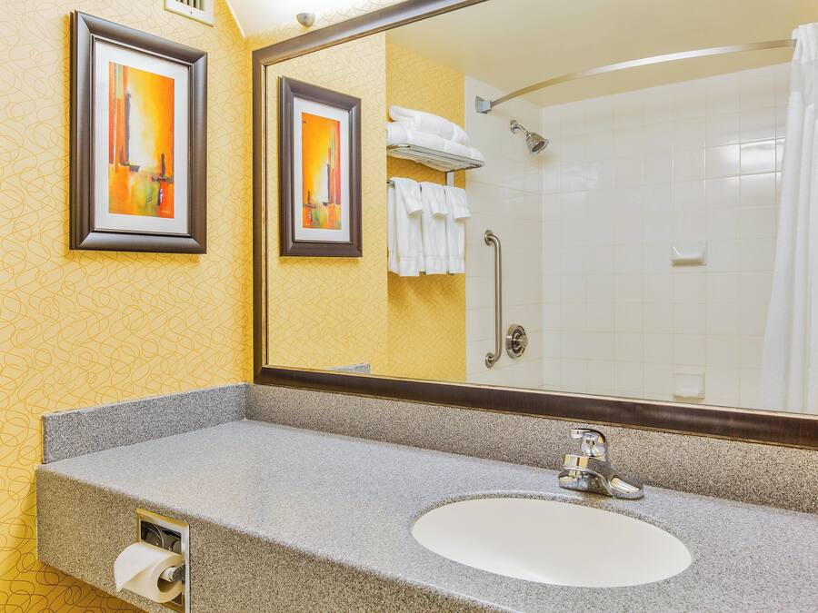 A bathroom with a granite countertop, a sink, a mirror, and a shower with a glass door.