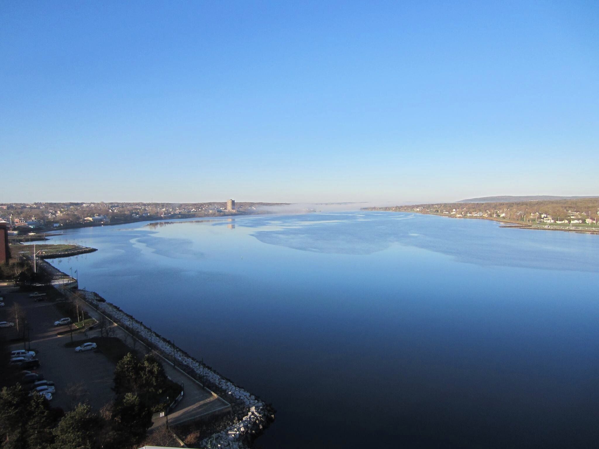 A large body of water with a bridge in the distance, surrounded by a cityscape.