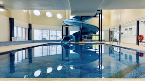 An indoor swimming pool with a spiral slide, large windows, and a lifebuoy. - Holiday Inn Sydney - Waterfront by IHG (Sydney)