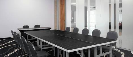 A conference room with a long table, chairs, and a patterned carpet.
