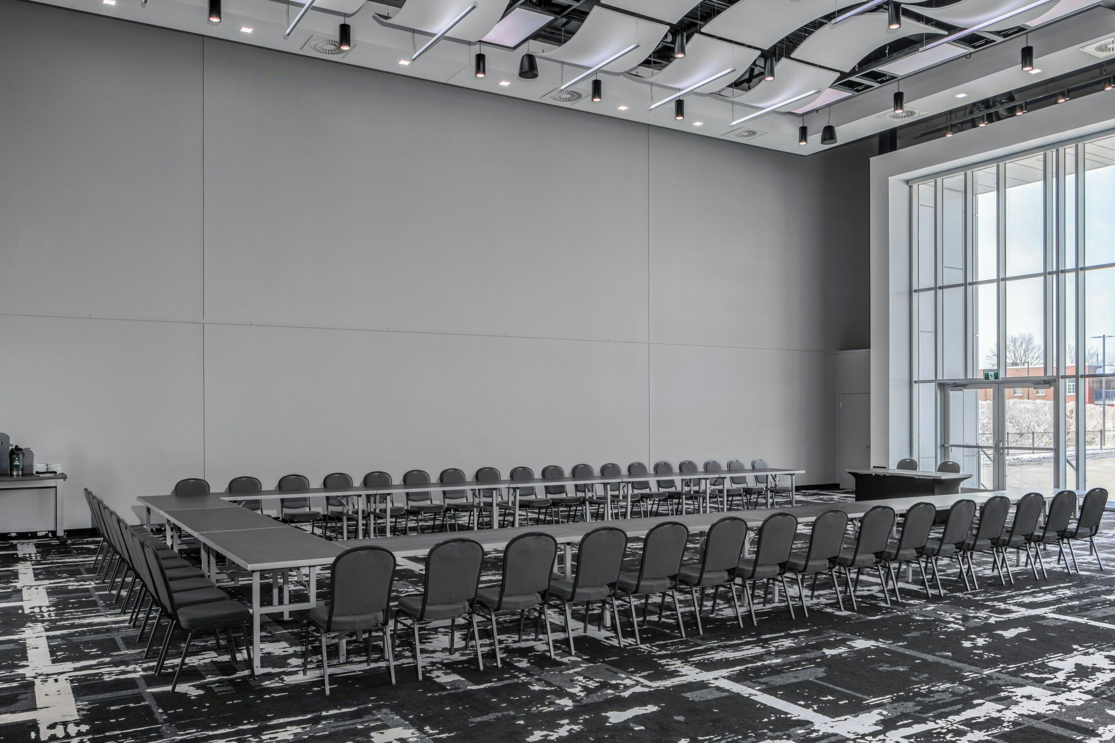 Un salón de conferencias con una larga mesa, sillas y un amplio ventanal.