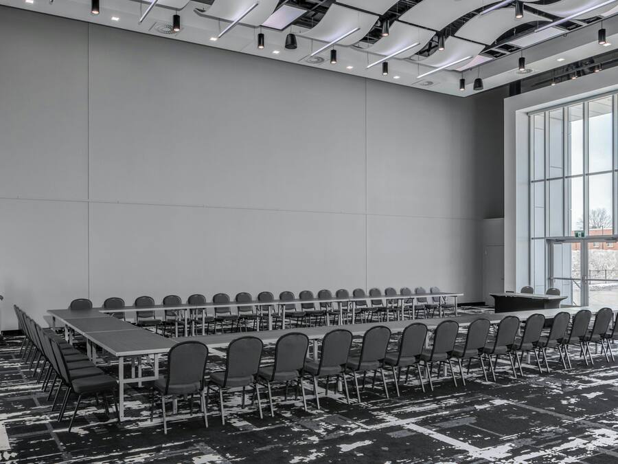 Un salón de conferencias con una larga mesa, sillas y un amplio ventanal.