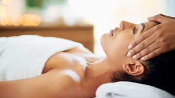 A person lying down with a towel wrapped around their upper body, receiving a massage.