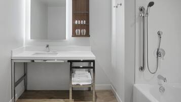 A modern bathroom with a white vanity, a mirror, a wooden medicine cabinet, a towel rack, and a walk-in shower with a bathtub.