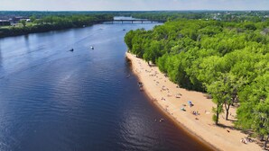 A riverside beach with boats, a bridge, and dense greenery. - Delta Hotels by Marriott Trois Rivieres Conference Centre (Trois-Rivieres)